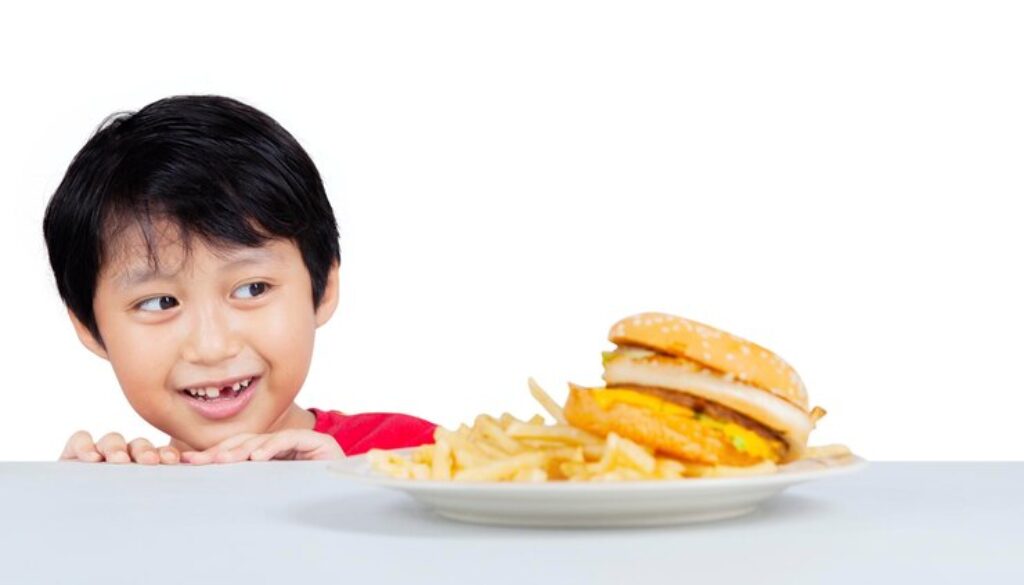 picture-cute-little-boy-peeping-tasty-hamburger-table-isolated-white-background_175634-30112